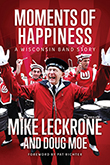 Moments of Happiness: Mike Leckrone, standing in front of the percussion session of the UW Madison marching band, his arms outstretched, a large smile on his face.